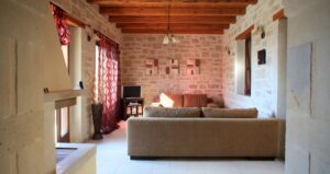 Interior photo of a sitting room in a holiday let cottage, with comfy sofa, light-coloured walls and TV screen.